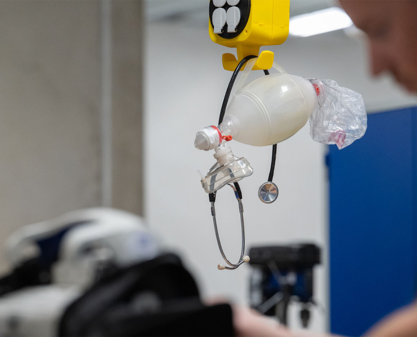 Ein Mann steht vor medizinischen Geräten Ein Mann steht vor medizinischen Geräten, im Fokus hängt ein Stetoskop und ein Beatmungsgerät von Mefina Medical