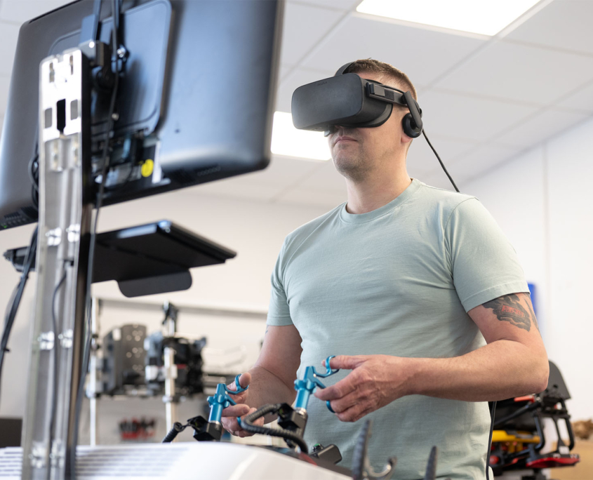 Mann mit VR-Headset steht an einem medizinischen Simulator Mann mit VR-Headset steht an LAP Mentor Laparoskopie-Simulator von Surgical Science