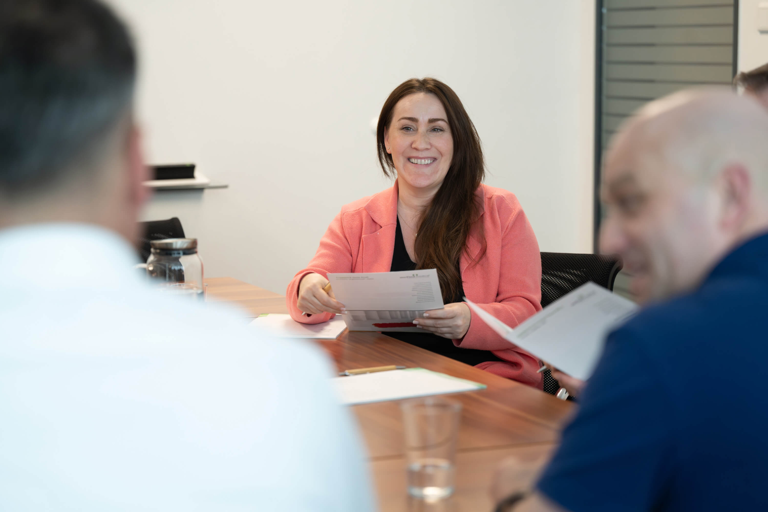 Ein gemeinschaftliches Miteinander bei Mefina Medical Eine Frau sitzt lächelnd an einem Tisch und hält ein Blatt Papier in der Hand