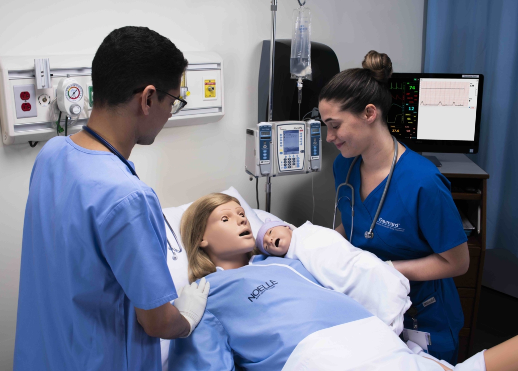 zwei Personen am Patientenbett des High-Fidelity-Simulators von Gaumard