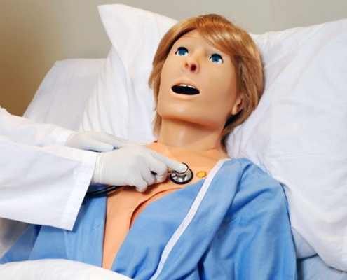 Arzt hört mit Stethoskop das Herz des Pflege-Patientensimulators ab