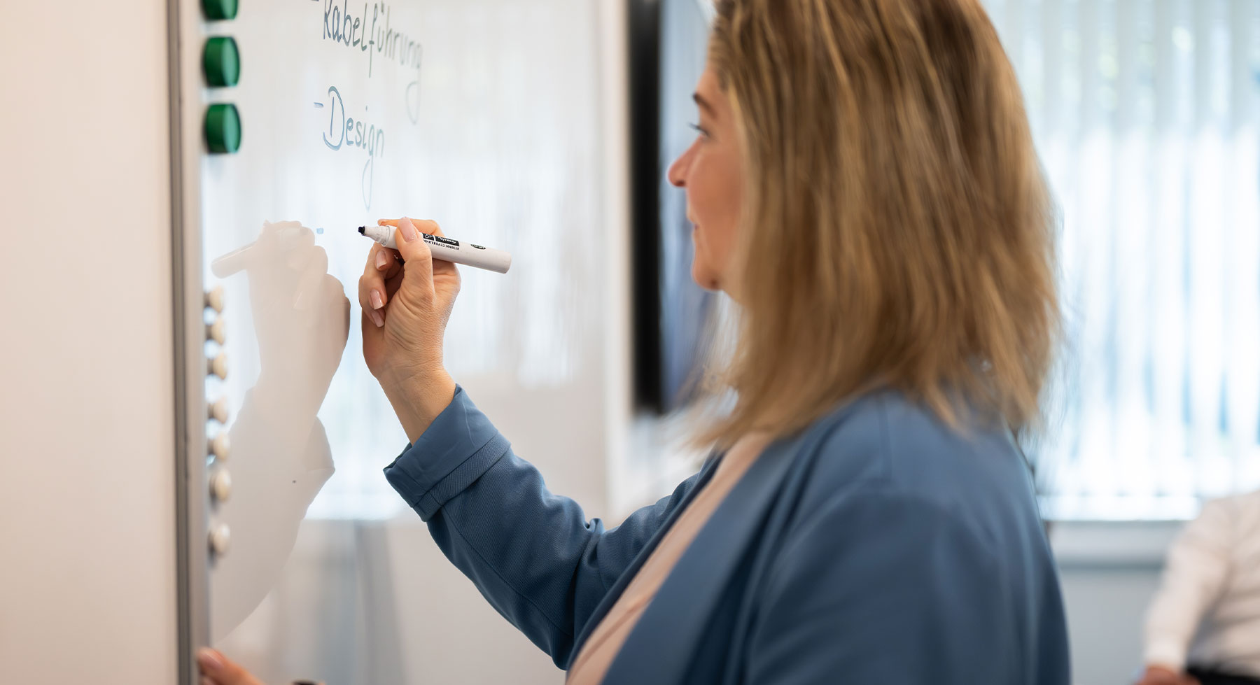 Frau steht mit Stift in der Hand vor einem White-Board