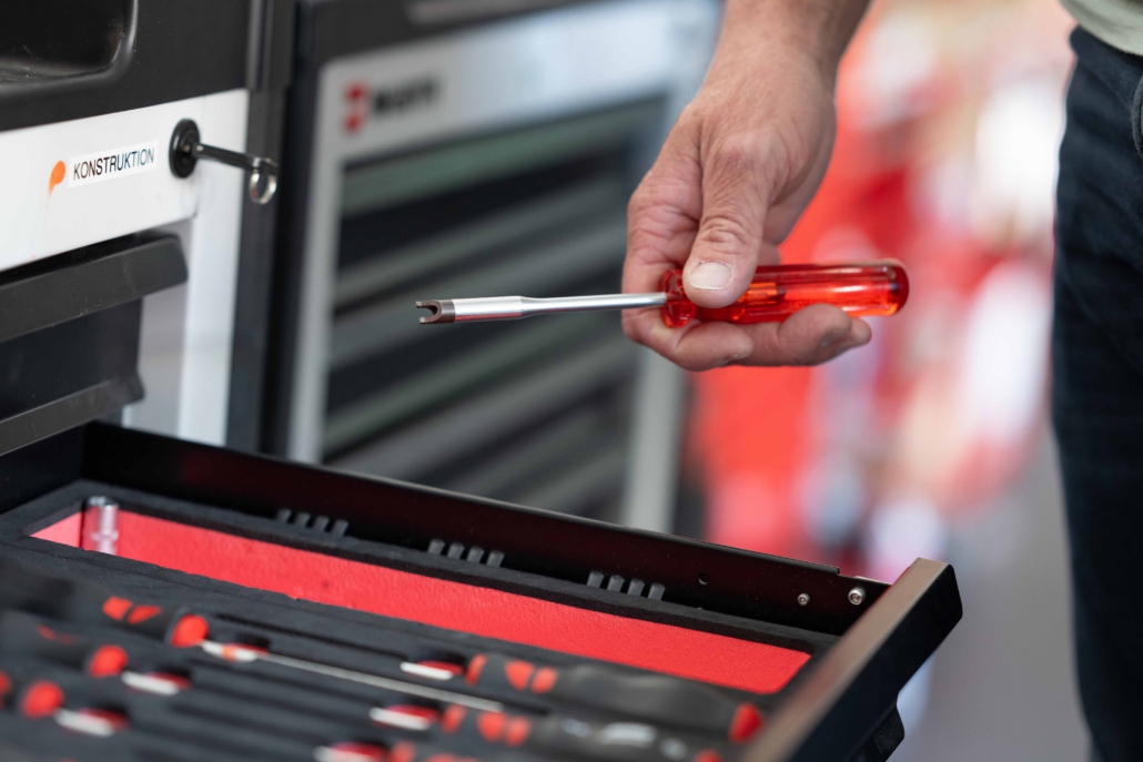 Hand eines Mefina Medical-Mitarbeiters legt Werkzeug in Schubladenfach zurück