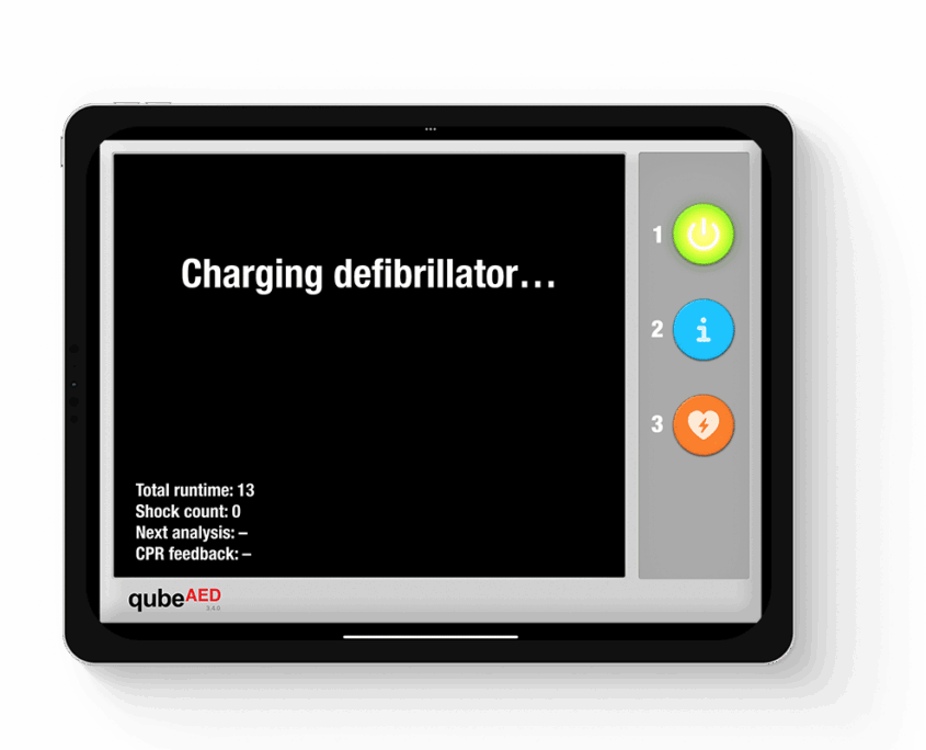 qubeaed_mockup_03web Tabletansicht des qubeAED von Skillqube mit dem Text "Charging defibrillator..." auf der Mitte des Displays