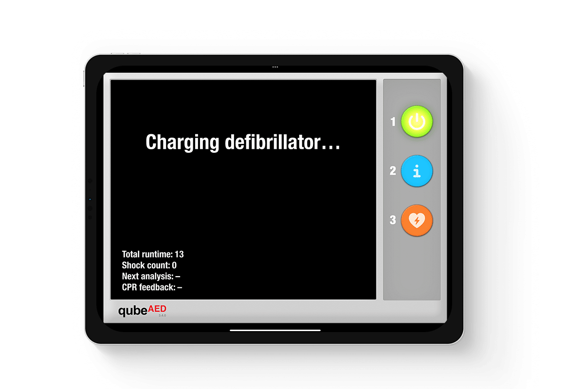 qubeaed_mockup_03web Tabletansicht des qubeAED von Skillqube mit dem Text "Charging defibrillator..." auf der Mitte des Displays