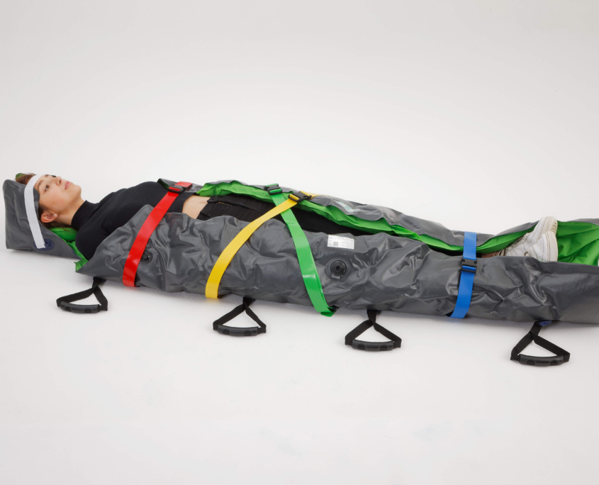 Frau liegt in Vakuummatratze, gesichert mit 5 bunten Gurten