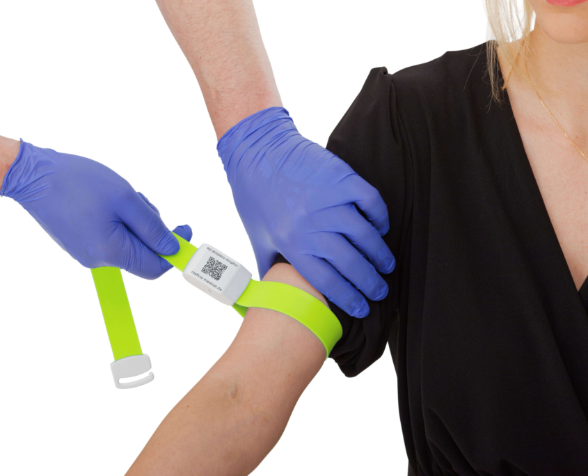 DaisyGrip_Gelb gelber Venenstauer angebracht an Oberarm einer Patientin. Arzt zieht Venenstauer an Arm fest.